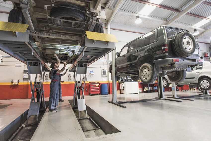 Car mechanics working under a car